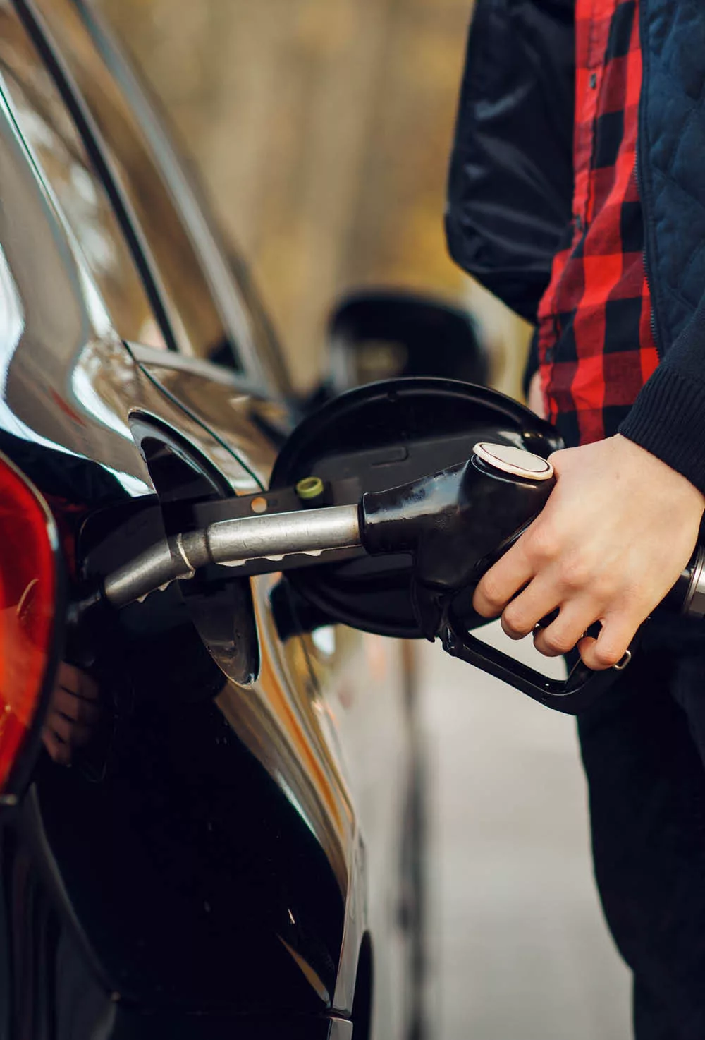 A man putting gasoline in his vehicle